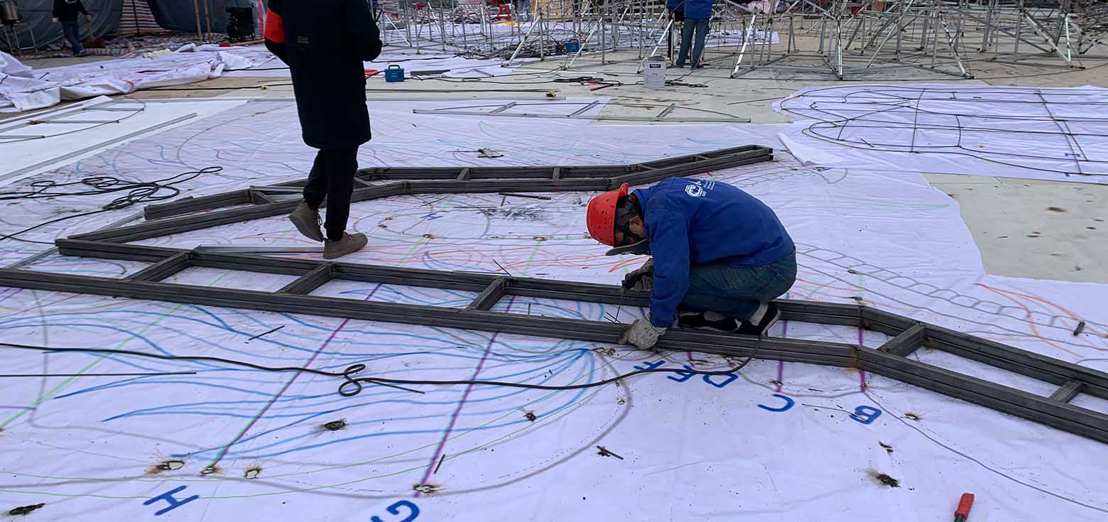 Custom IP Structures 6 Workers welding steel frames on floor templates for commercial lantern fabrication.