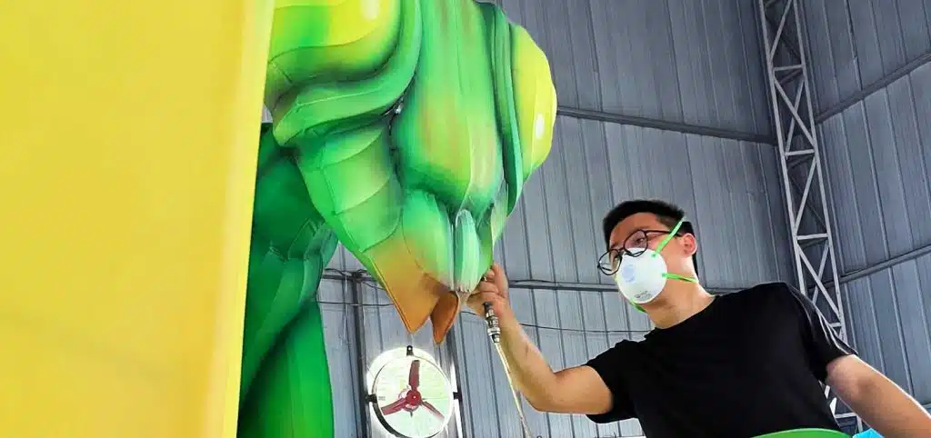 The artist is applying color to the mantis-shaped Chinese lantern lights.