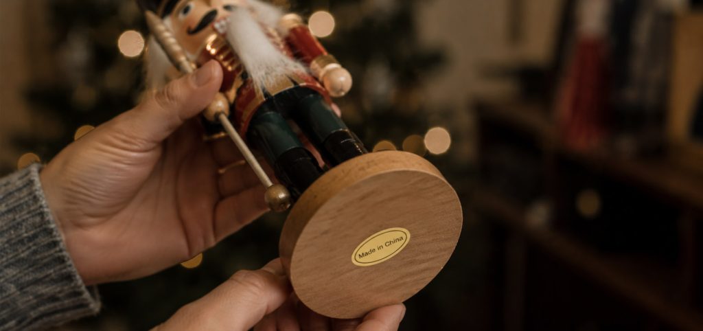 BLOG 2 Hände halten einen Nussknacker mit einem Weihnachten Made in China Aufkleber.