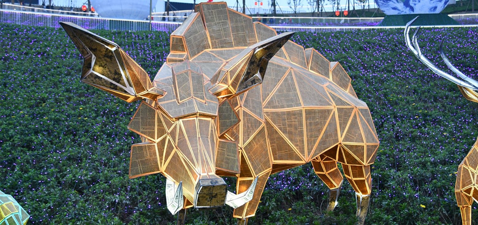 An artistic, modern lantern shaped like a wild boar in a city park.