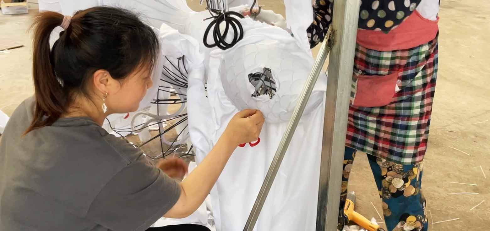 workers are pasting silk onto the framework of a traditional Mid-Autumn Festival lantern.