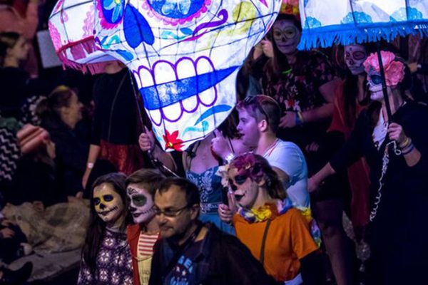 A lively lantern parade scene featuring an unusual skull-shaped parade lantern.