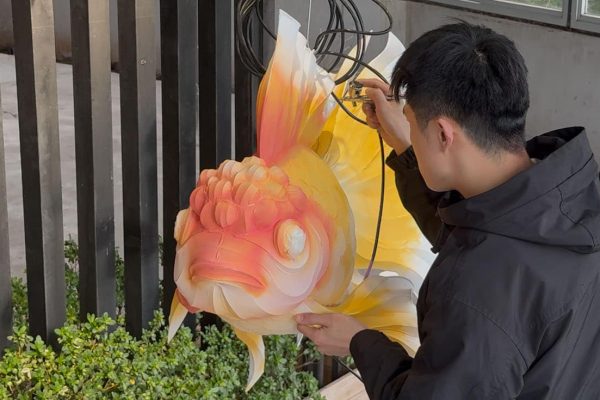 Artisan airbrushing colors on goldfish lantern during Chinese lantern making process