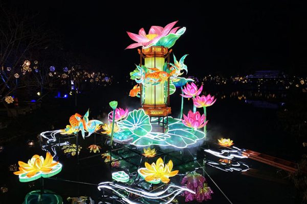 A massive, visually stunning set of large-scale floating lanterns on the scenic lake at night.