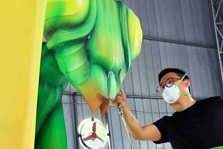 The artist is applying color to the mantis-shaped Chinese lantern lights.