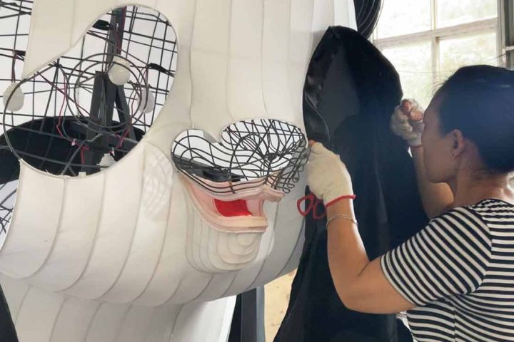 Workers are papering a giant panda lantern.