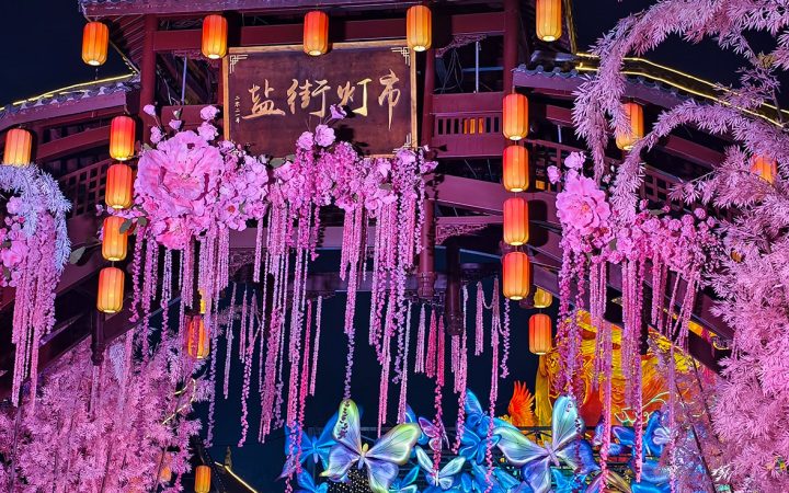 Una puerta de mercado de faroles tradicionales adornada con faroles florales rosas, evocando historias clásicas del Festival del Medio Otoño.